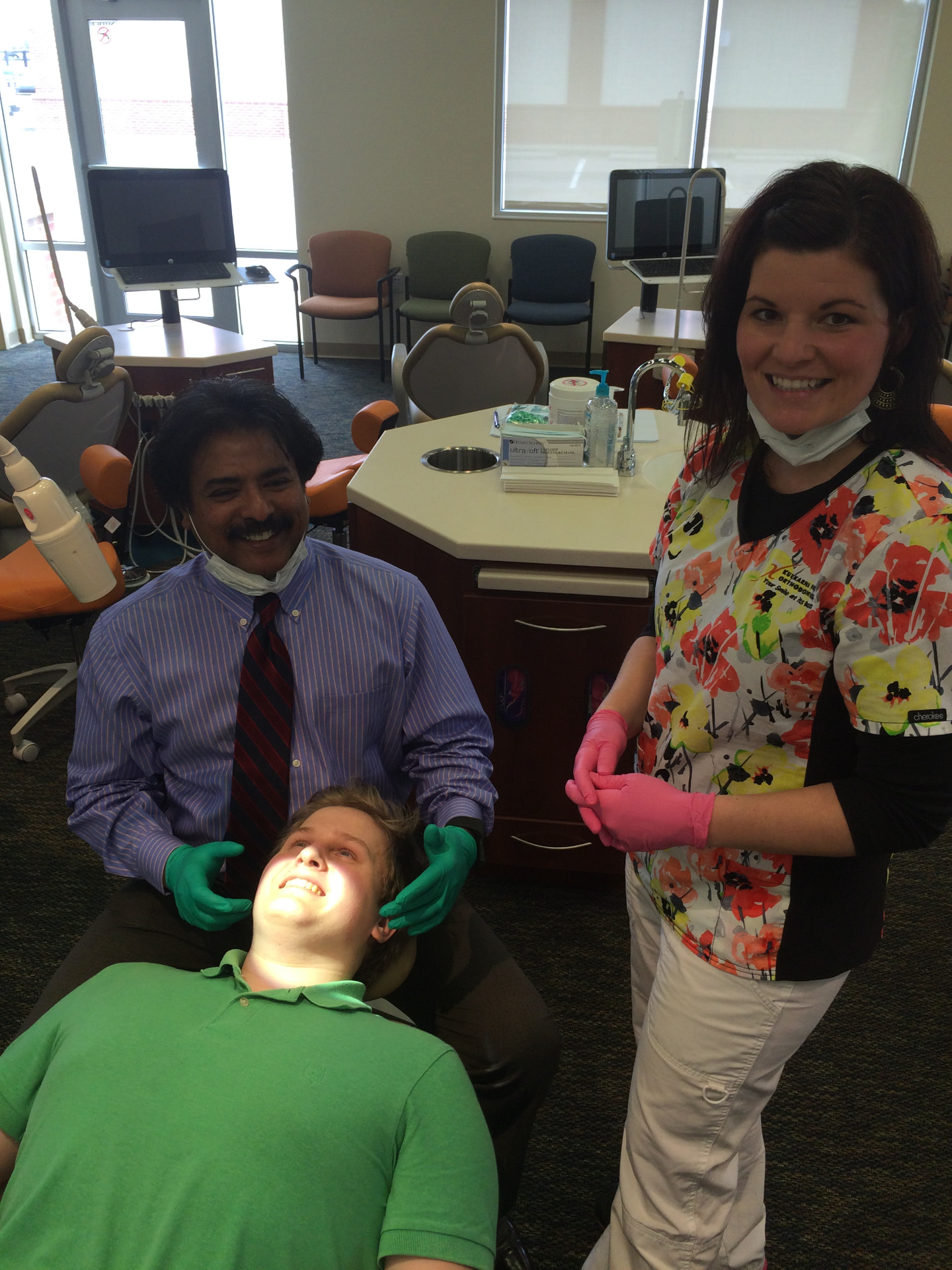 Dr. Kulkarni and team member smiling with a patient after treatment